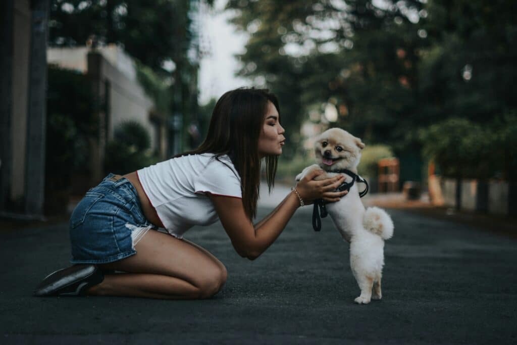 woman kneeling kissing her dog