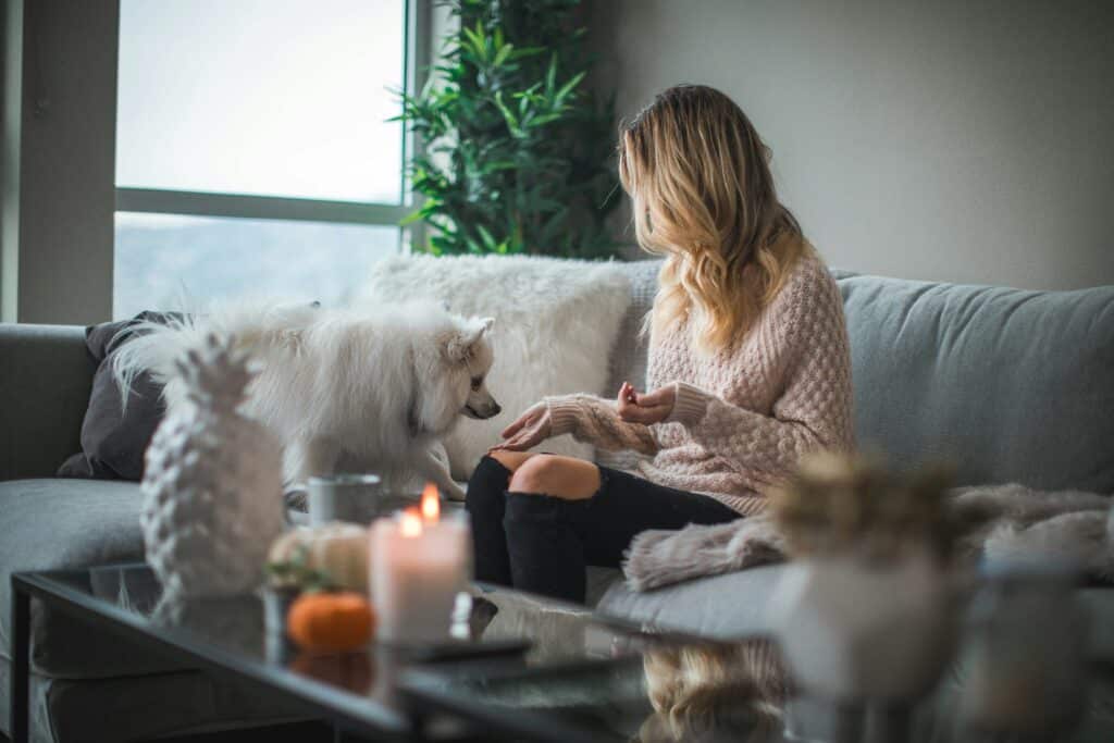 a woman giving her dog treats inside her home